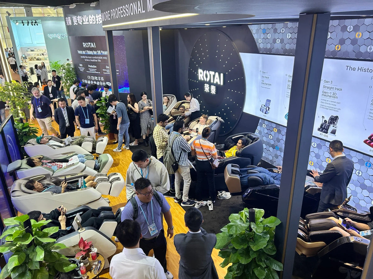 Crowded trade show booth with people testing ROTAI massage chairs at an exhibition.