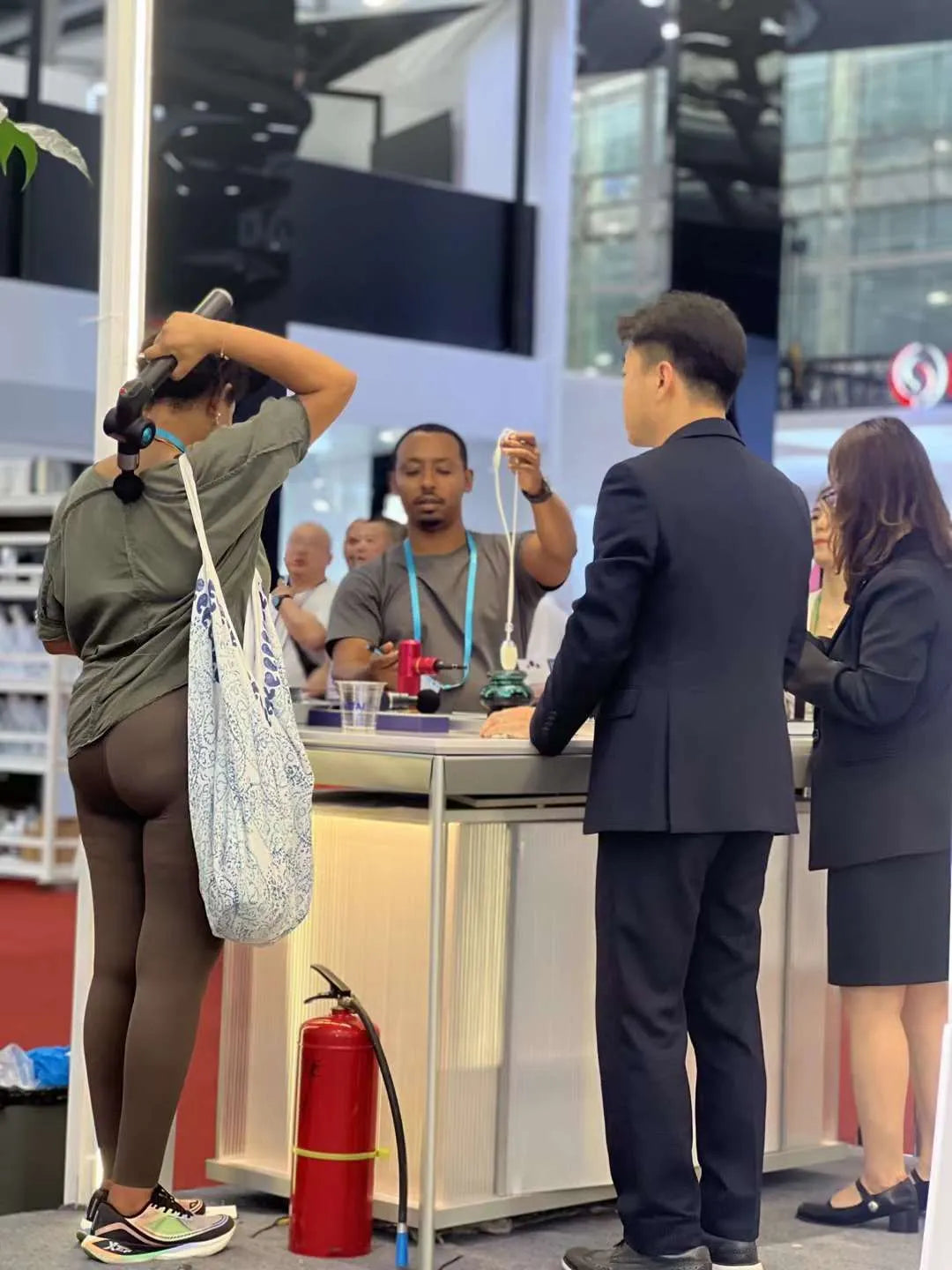 People interacting at an exhibition booth, with a fire extinguisher nearby.